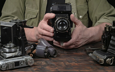 An elderly collector studies old cameras. Close-up.