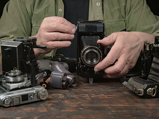 An elderly collector studies old cameras. Close-up.
