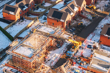 Aerial view of Construction site with yellow mobile crane and scaffolding in winter with snow...
