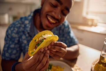 Close up of black man eating tacos.