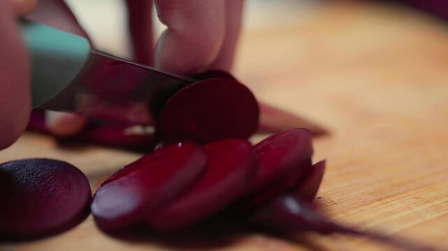 Closeup of hands cutting fresh beetroots on a  cutting board. Process of preparing beetroot for cooking. Local food concept.	
