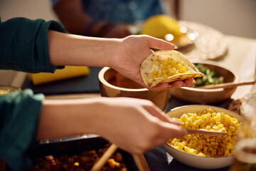 Close up of woman eating tacos while having Mexican food for lunch with friends.