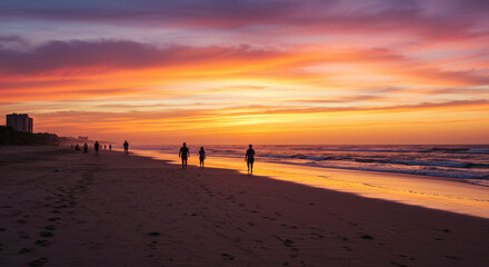 Silhouette of People Walking Along Shoreline during Sunset with Colorful Sky and Ocean Reflection