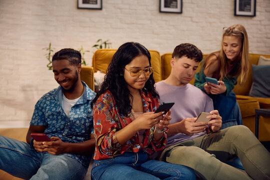 Young Indian woman and her friends using their smart phones at home.