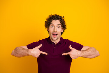 Portrait of a cheerful man pointing at himself against a vibrant yellow background, celebrating...
