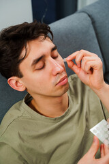 Obraz premium Young guy sticking acne patches to forehead to clean skin from zits. Using acne patches for facial skincare.