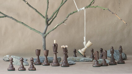 chess piece white rook hanging on noose among black chess pieces