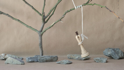 chess piece white king hanging on noose among stones