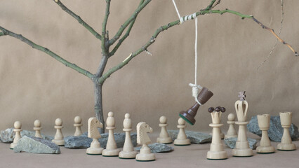 chess piece black rook hanging on noose among white chess pieces