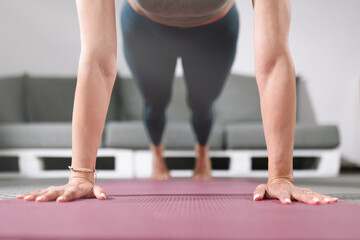 Woman practicing plank on a yoga mat in a modern fitness studio during workout session