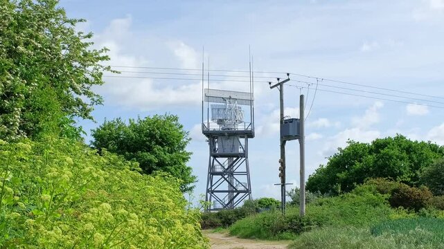 Rotating radar detector carrying out important surveillance on top of a tower in the countryside. Panning shot