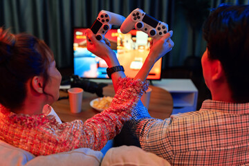 Couple gamer with hands cross of joystick playing fighting competition video game together on tv...
