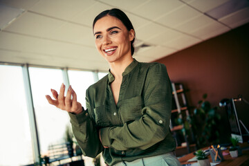 Smiling young female business professional in a green blouse engaged in a positive conversation in...