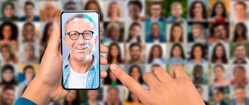 A person uses a smartphone to scan their face for identification purposes. The screen displays a facial recognition overlay, while various portraits are blurred in the background.