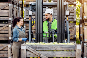 Manager work with worker on storage. Happy young bearded guy driver in helmet in forklift truck...