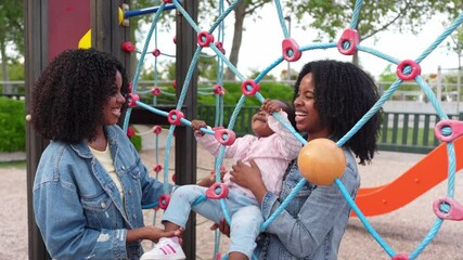 Twin sisters laughing and playing with their niece at the playground, soaking up the sun and creating joyful memories together - Powered by Adobe
