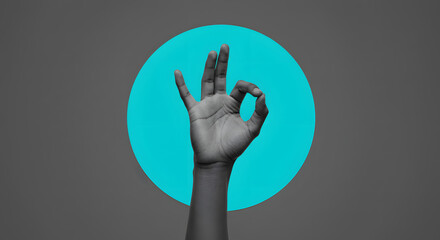 Obraz premium Ok hand gesture in grayscale with turquoise circle and gray background