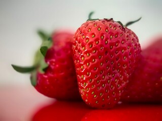 Strawberries on the red ground with reflection. Juicy, fresh strawberry