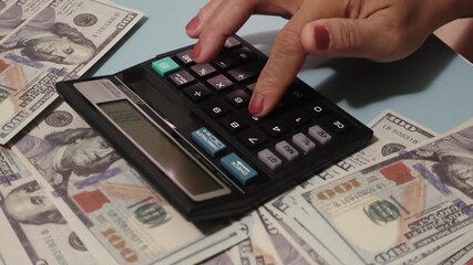 Woman hands pressing calculator buttons analyzing business income. Hand using calculator on table with spread US dollar banknotes. - Powered by Adobe