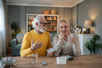 Senior couple taking medicine during online medical consultation