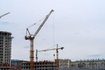 Construction of high-rise residential buildings against the backdrop of a gray cloudy sky