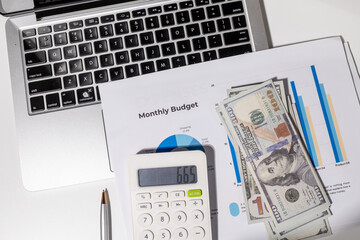 A monthly budget graph paper is placed on the desk alongside a calculator, laptop, and...