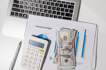 A monthly budget graph paper is placed on the desk alongside a calculator, laptop, and...