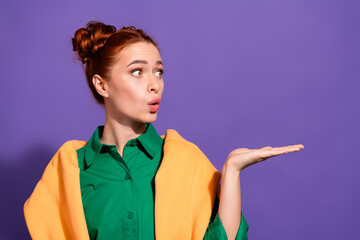 Stylish young red haired woman wearing vibrant green shirt and orange scarf, posing in gesture on...