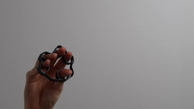 Hand Exerciser Training Fingers and Grip Strength with Copy Space.  Hand using silicone exerciser to train grip and finger strength on white background with copy space