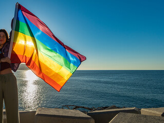 Smiling woman with LGTBI flag in the wind.