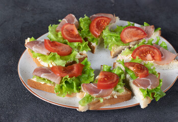 Homemade sandwiches with bacon, tomato and lettuce on white plate