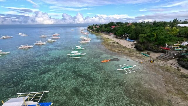 flying drone above colourful boats in the Philippines cebu moalboal sunny day with crystal clear water 
