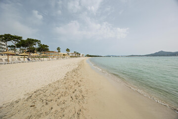 Empty beach with umbrellas and sunbeds in playa de muro, mallorca