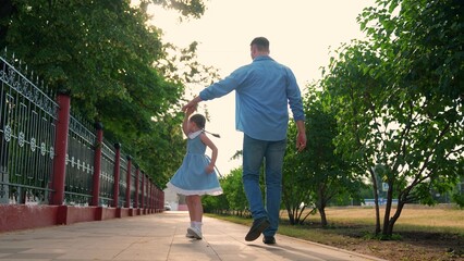 Child daughter walking with father dancing on street. Carefree dad daughter enjoying walk on street happy girl spinning dancing. Happy family. Fathers day child leisure. Cute child having fun with dad