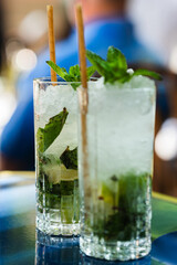 Mojito in glass with mint, lemon, ice and straw. Suitable for illustrating summer drinks, cocktail recipes, or bar menus.