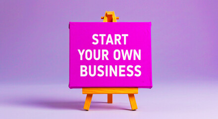 A purple canvas on a wooden easel with the words start your own business in white lettering shown