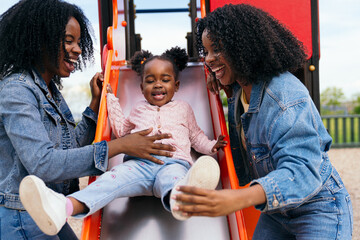 African two twin sisters are playing with their niece at the playground, enjoying a sunny day...