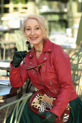 Gray-haired woman in her sixties in a red leather jacket in a restaurant in the city