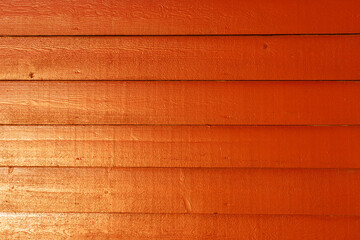 Bright orange texture of the wooden wall of a traditional Norwegian fisherman's cabin by the sea, an ideal background for design with pronounced wood grain.