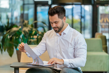 Caucasian young businessman working with documents, analyzing information, reading papers prepare...
