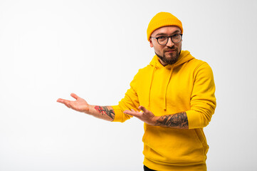 Confident bearded man in yellow hoodie and beanie pointing sideways with serious face. Isolated on...