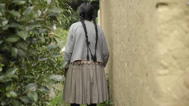 An elderly indigenous woman walking slowly in a traditional adobe house in the countryside, Bolivia.
