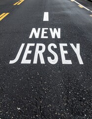 Road surface with new jersey text painted in white on asphalt background