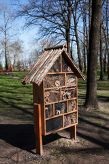 Wooden insect house in spring green garden. Nest sites for solitary bees, ants, wasps, butterflies,...