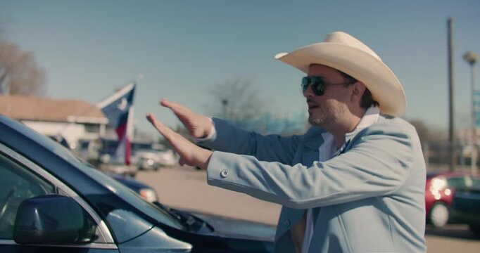 Car Salesman Wearing Cowboy Hat Showing Off Cars At Car Dealership