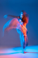 Female jazz-funk dancer captured in a long-exposure motion blur with neon lighting, conveying explosive energy, rhythm, and creative expression on a dramatic studio backdrop.