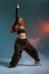 Confident jazz-funk dancer strikes a powerful pose in dramatic studio lighting with smoke effects, showcasing strength, rhythm, and bold street dance attitude.