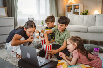 boys and girls eat pop corn and watch movie on laptop