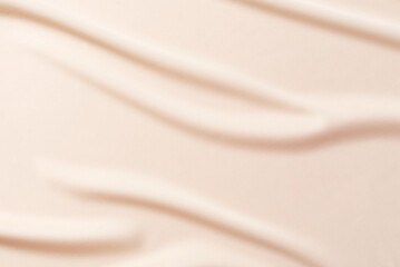 Fototapeta premium Abstract nude background. Soft beige, nude silk satin fabric with soft wavy folds