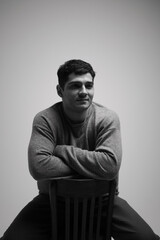 Capturing confidence in a studio setting with a young man posing thoughtfully on a chair